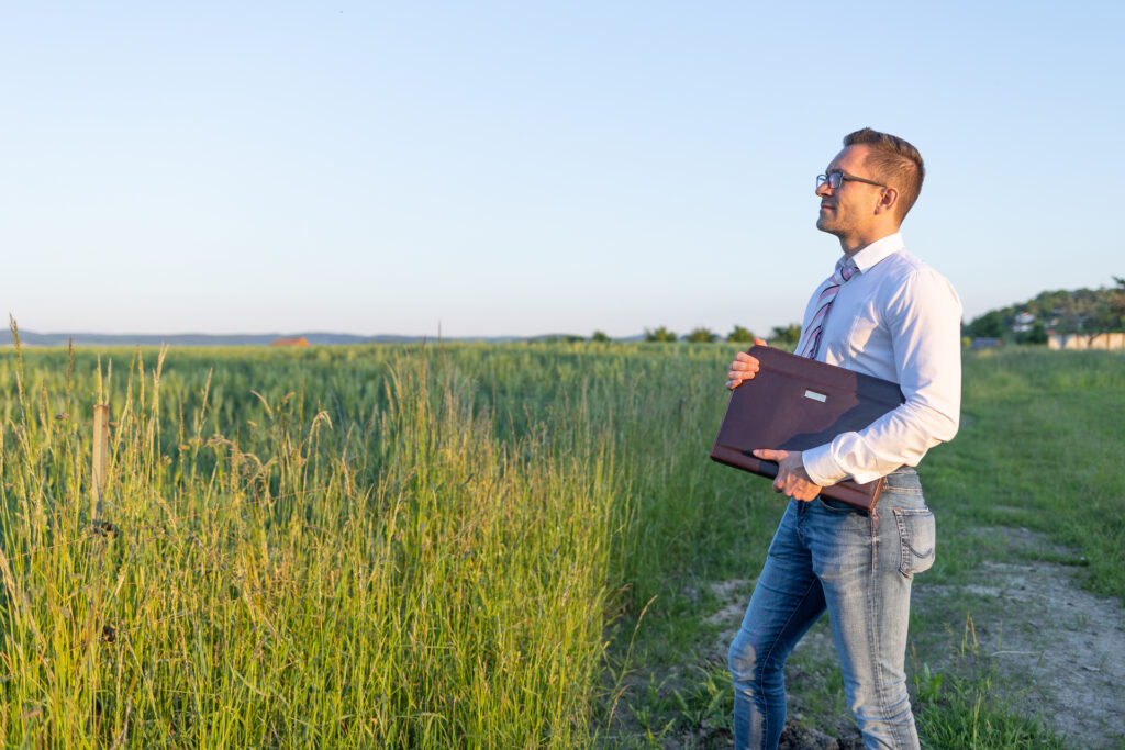 Mann mit Aktenmappe an einer Wiese
